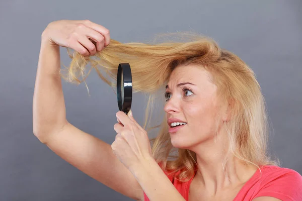 Woman looking at hair through magnifying glass — Stock Photo, Image