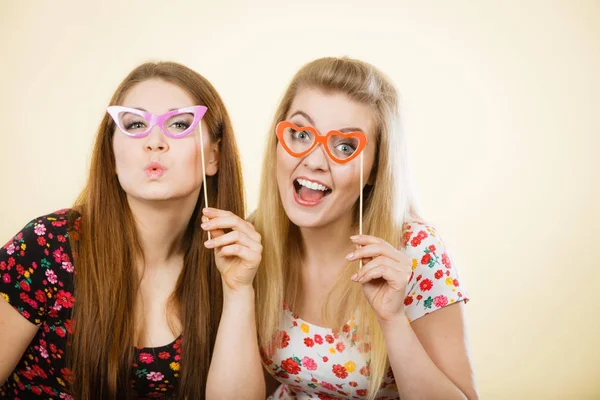 Two happy women holding fake eyeglasses on stick — Stock Photo, Image