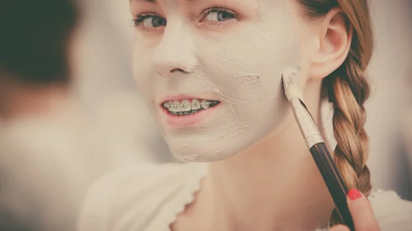 幸せな若い女の顔に泥マスクを適用します。 — ストック写真
