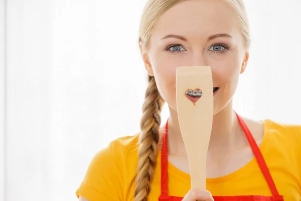 Woman holding wooden spatula with heart — Stock Photo, Image