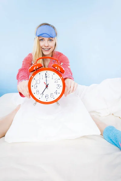Sleepy woman wearing pajamas holding clock — Stock Photo, Image