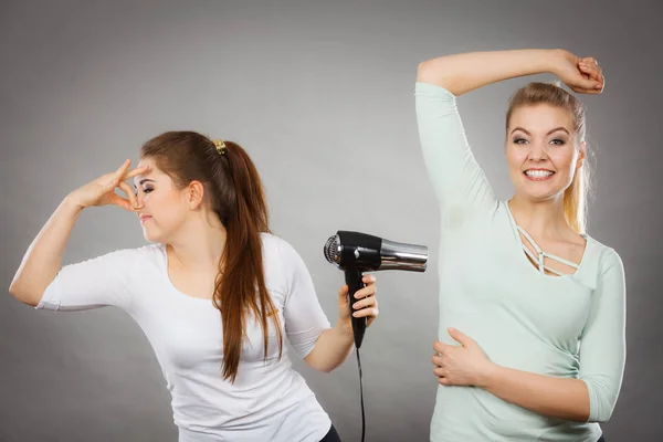 Woman drying friend armpit with hair dryer — Stock Photo, Image