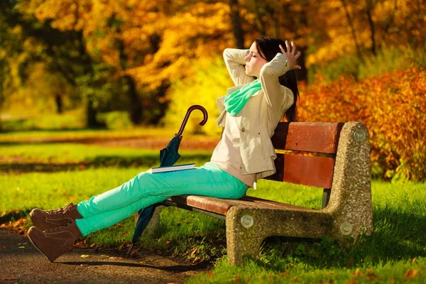 Женщина читает книгу сидя на скамейке в парке — стоковое фото