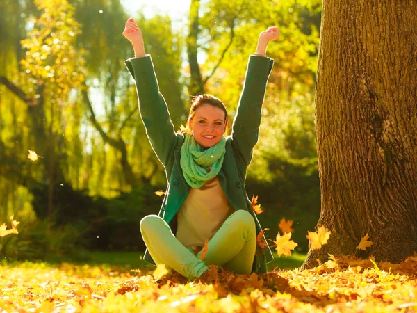 Gelukkige vrouw gooien herfst bladeren in park — Stockfoto