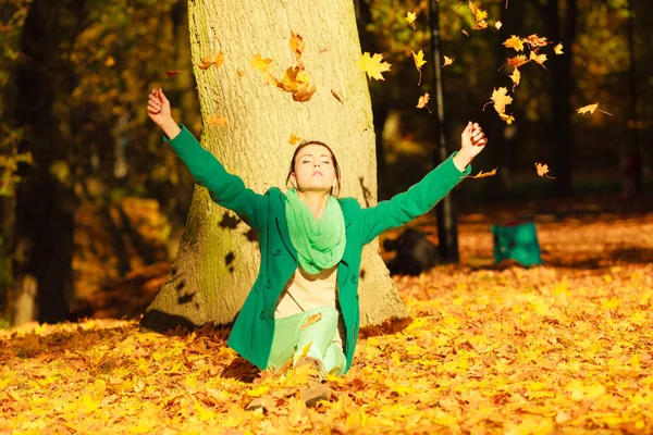 Gelukkige vrouw gooien herfst bladeren in park — Stockfoto