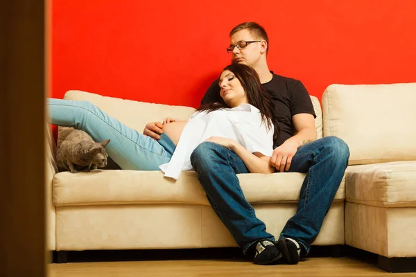 Mulher grávida e homem relaxante no sofá — Fotografia de Stock