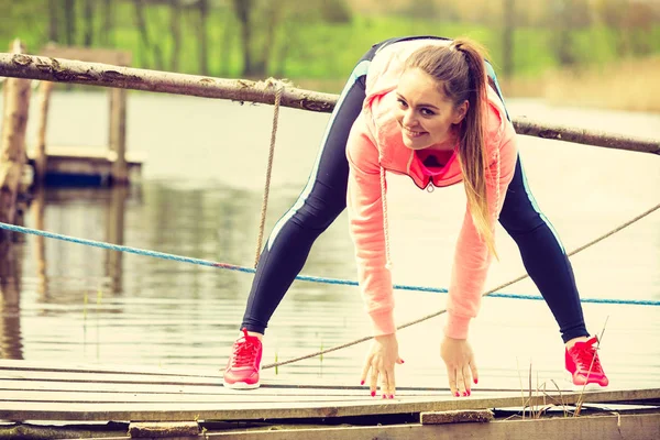 Girl training in sporty clothes on lake shore — Stock Photo, Image