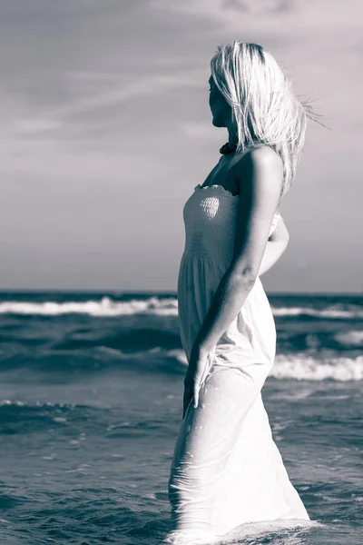 Blonde woman wearing dress walking in water — Stock Photo, Image