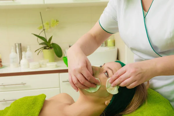 Beautician wiping off green mask on woman — Stock Photo, Image