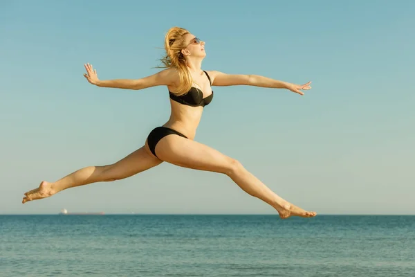 Kvinna som bär bikini spelar, hoppning nära havet — Stockfoto