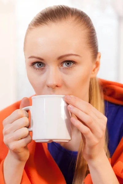 Mujer acostada en un sofá bajo una manta bebiendo té —  Fotos de Stock