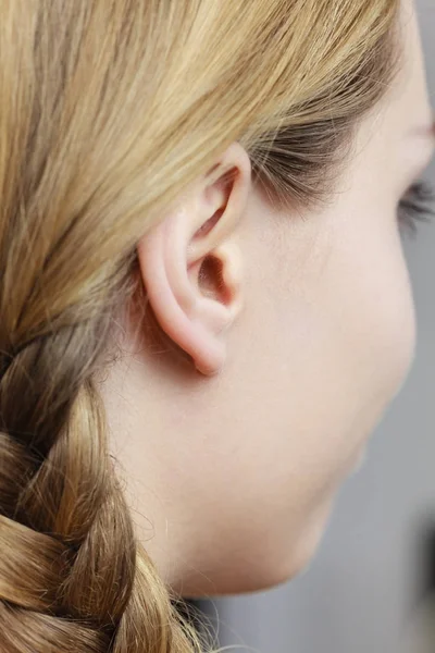 Primer plano en la oreja femenina y cabello trenzado — Foto de Stock