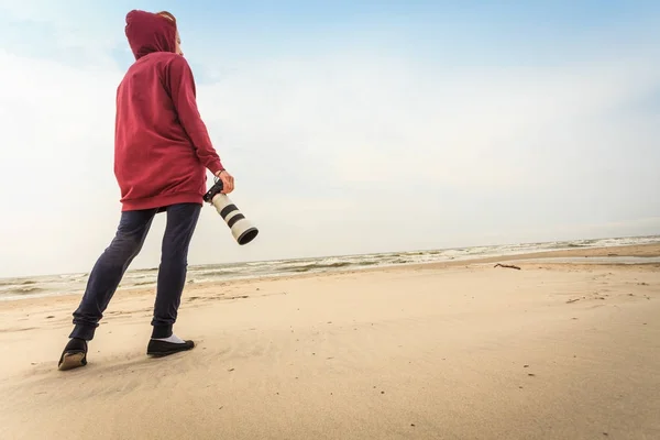 Kobieta spacerująca po plaży z kamerą — Zdjęcie stockowe
