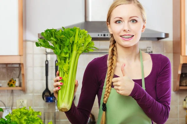 Femme dans la cuisine tient céleri vert — Photo