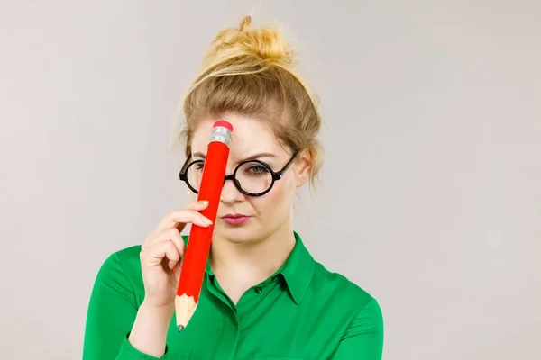 Mujer confundida pensando, lápiz grande en la mano — Foto de Stock