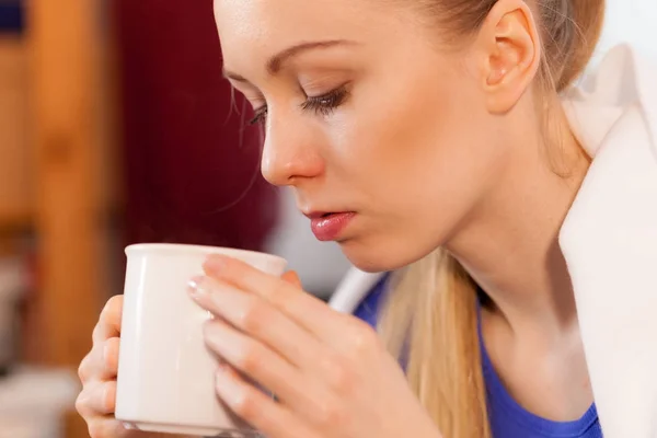 Mujer acostada en un sofá bajo una manta bebiendo té — Foto de Stock