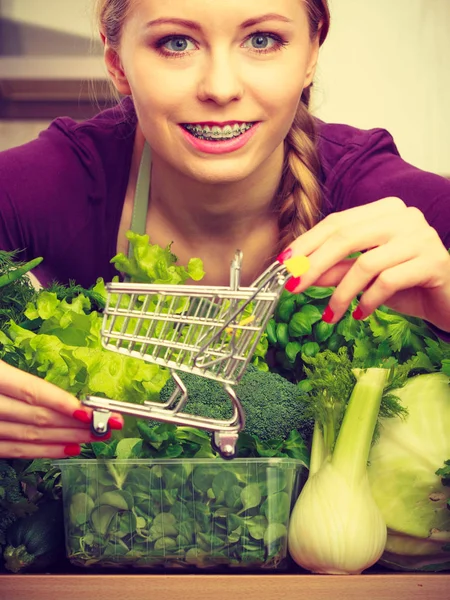 Mujer en cocina teniendo verduras sosteniendo carrito de la compra —  Fotos de Stock