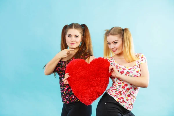 Feliz dos mujeres sosteniendo almohada en forma de corazón —  Fotos de Stock