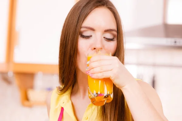 Donna in cucina bere succo d'arancia fresco — Foto Stock