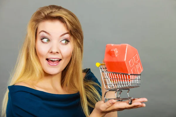 Vrouw met winkelwagentje met huis binnen — Stockfoto