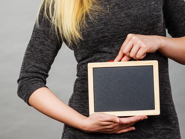 Woman holding blank black board on stomach — Stock Photo, Image