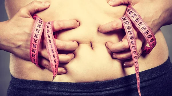 Mujer tocando estómago sosteniendo cinta métrica —  Fotos de Stock