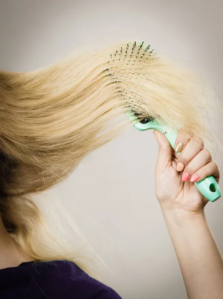 Unrecognizable blonde woman brushing hair — Stock Photo, Image