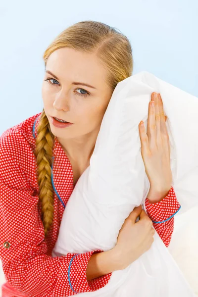 Young woman wearing pajamas hugging soft pillow — Stock Photo, Image