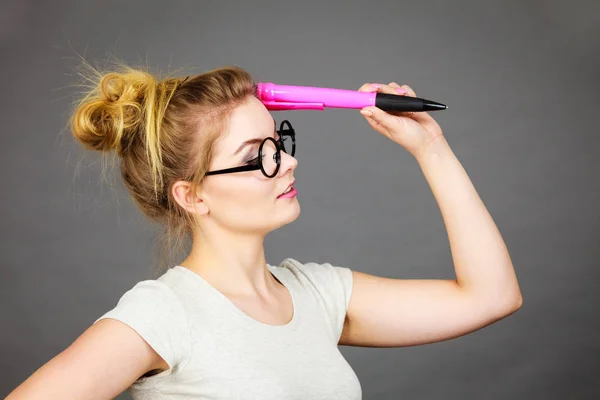 Mujer sosteniendo un gran lápiz de gran tamaño pensando en algo —  Fotos de Stock