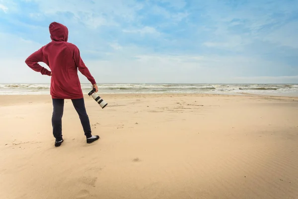 Woman walking on beach with camera — Stock Photo, Image