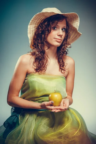 Mulher de vestido e chapéu segurando maçã amarela . — Fotografia de Stock