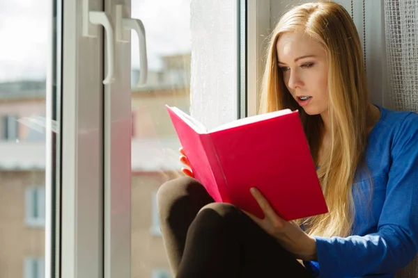 Woman reading on windowsill — Stock Photo, Image