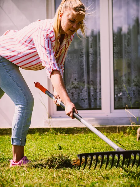 Mulher usando ancinho para limpar o jardim — Fotografia de Stock