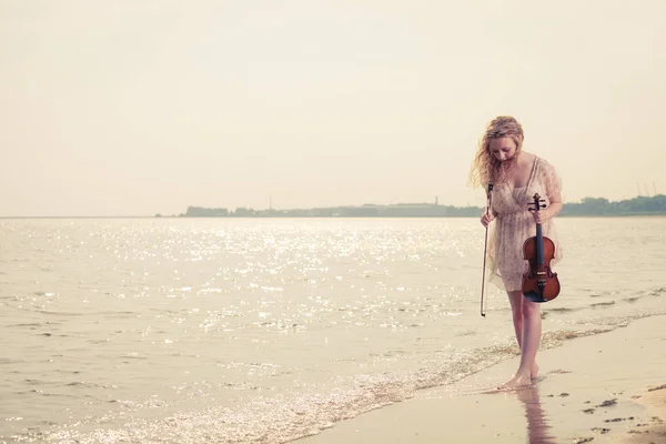 Kvinna på stranden nära havet håller fiol — Stockfoto