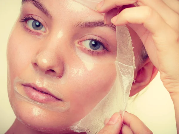 Kvinna att ta bort facial peel off mask. — Stockfoto