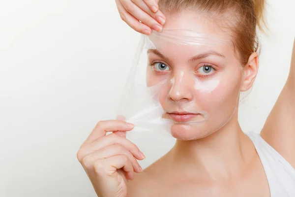 Kvinna att ta bort facial peel off mask. — Stockfoto