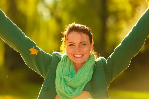 Gelukkige vrouw gooien herfst bladeren in park — Stockfoto