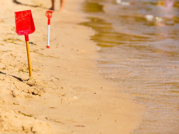 Zwei rote Spielzeugschaufeln im Sand am Strand — Stockfoto