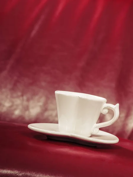 Pequeno chá branco de xícara de café no sofá vermelho — Fotografia de Stock