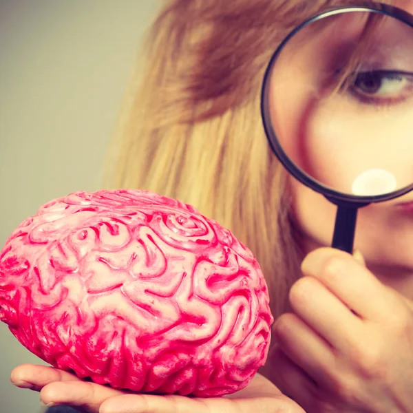 Женщина с увеличительным стеклом исследует мозг — стоковое фото