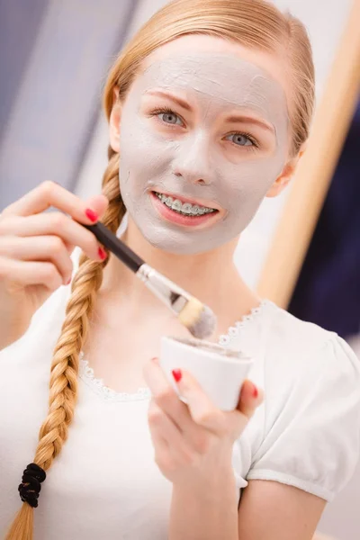 Gelukkig jonge vrouw modder masker aanbrengen op gezicht — Stockfoto