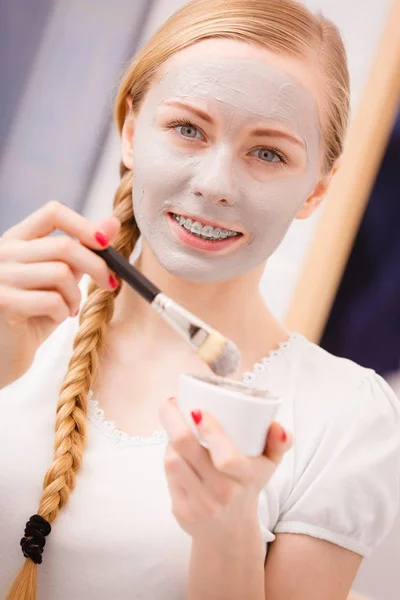 Mujer joven feliz aplicando máscara de barro en la cara — Foto de Stock