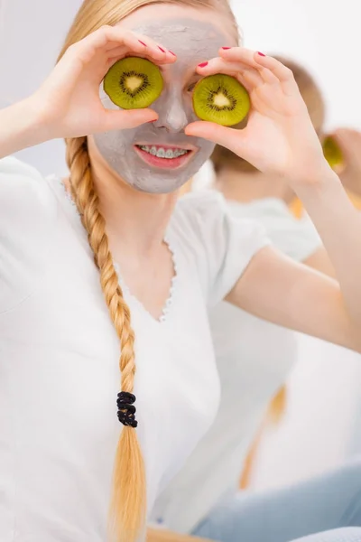 Jovem feliz tendo máscara facial segurando kiwi — Fotografia de Stock