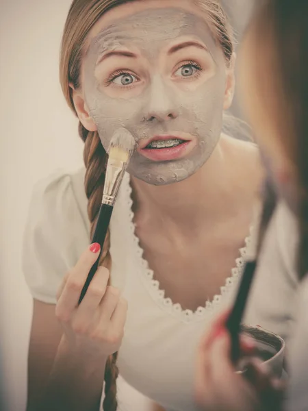 Happy young woman applying mud mask on face — Stock Photo, Image