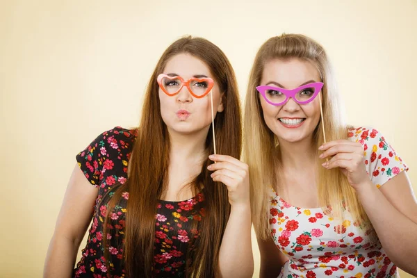Dos mujeres felices sosteniendo anteojos falsos en palo —  Fotos de Stock