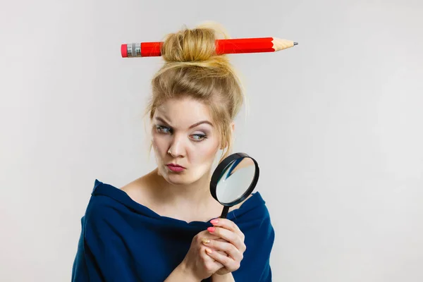 Mujer sosteniendo lupa con lápiz para el cabello — Foto de Stock