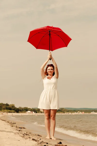 Pelirroja caminando en la playa sosteniendo paraguas — Foto de Stock