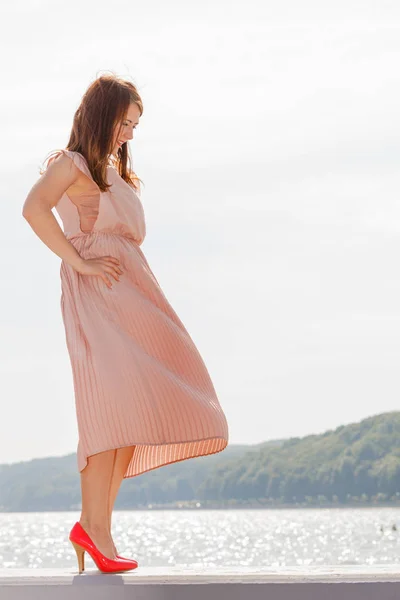 Vrouw lang licht roze jurk dragen op steiger — Stockfoto