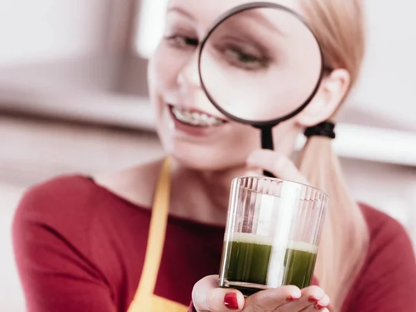 Kobieta, patrząc na sok warzywny przez szkło powiększające — Zdjęcie stockowe