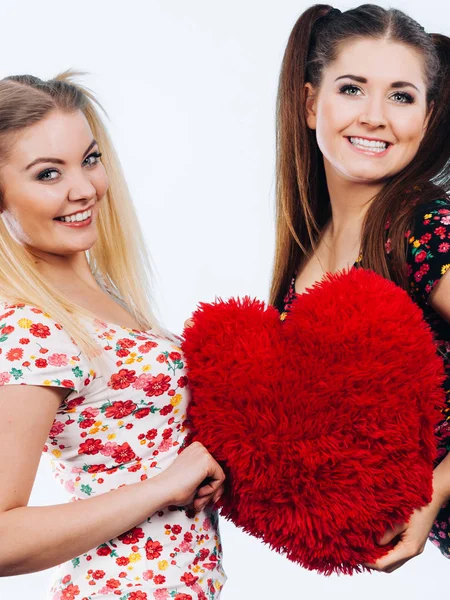 Gelukkig twee vrouwen bedrijf hartvormige kussen — Stockfoto